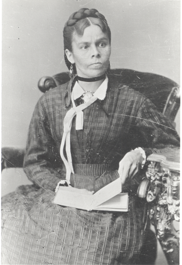 Original title:  Courtesy of The Grey Roots Archival Collection. Nahebahwequay/Catherine Sutton, [ca/ 186?] (seated, book in lap, white ribbon at neck).